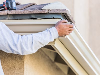 man in white sweater repairing gutter of a house