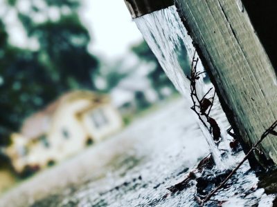 Rainwater flowing out of a residential gutter and downspout during a rainstorm